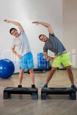 Portrait of two men doing aerobic exercise with stepper