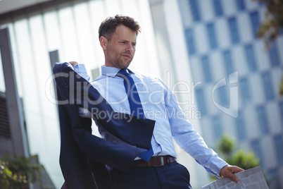 Businessman holding blazer and newspaper