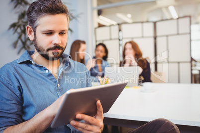 Businessman using digital tablet against female coworkers