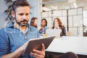 Businessman using digital tablet against female coworkers