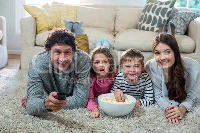 Family watching television while lying on the floor