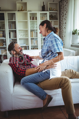 Happy woman sitting on mans lap in living room
