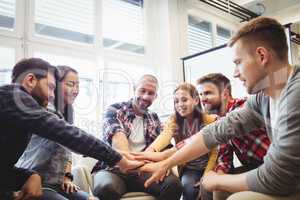 Creative business people stacking hands in meeting room