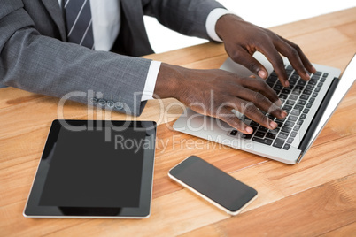 Mid section of businessman using laptop and other multimedia devices