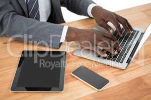 Mid section of businessman using laptop and other multimedia devices