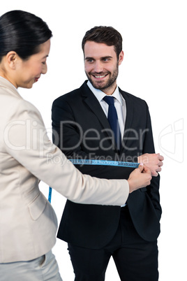 Smiling businesswoman measuring businessman sleeve