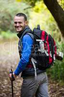 Smiling male hiker walking with hiking pole