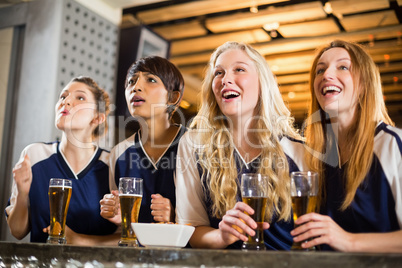 Female fan watching football at bar counter