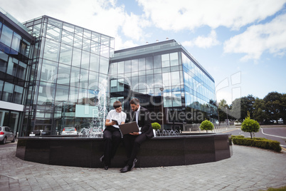 Businesspeople discussing on digital tablet and laptop