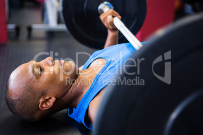 Determined male athlete exercising with barbell