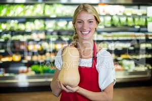 Smiling female staff holding a vegetable in organic section