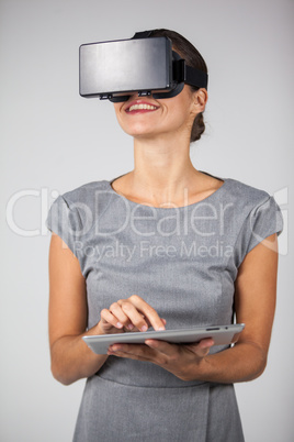 Woman holding digital tablet and using virtual reality headset