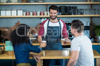 Waiter serving a coffee to customer at counter