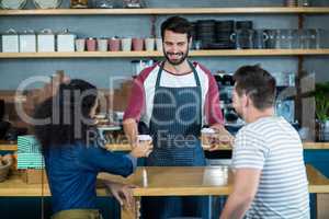 Waiter serving a coffee to customer at counter