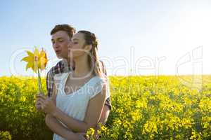 Couple holding blowing pinwheel in mustard field