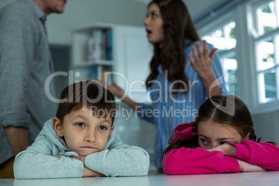 Upset children sitting while couple arguing with each other