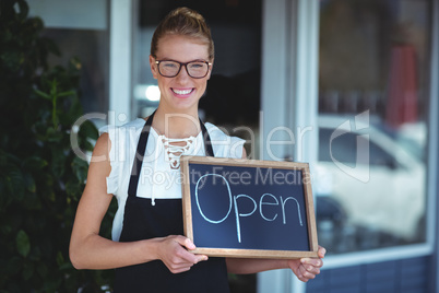 Portrait of waitress standing with chalkboard