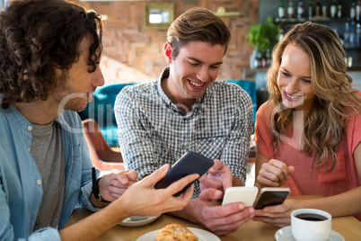 Smiling friends using their mobile phone