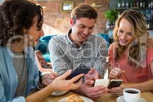 Smiling friends using their mobile phone