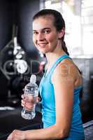 Happy female athlete holding water bottle