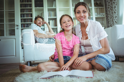 Mother and daughter sitting on the floor and looking at photo album