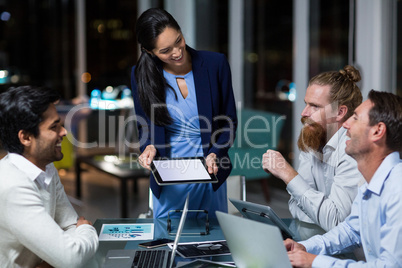 Businesswoman discussing with colleagues over digital tablet