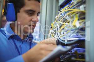 Technician maintaining record of rack mounted server on clipboard