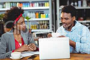 Man and woman using a laptop while having cup of coffee