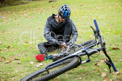 Male cyclist tying a shoelaces in park