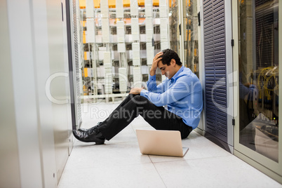 Stressed technician sitting in hallway