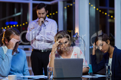Tensed businesspeople working on laptop