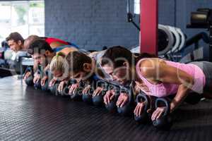 People doing push-ups with kettlebell in gym