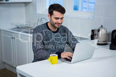 Man using laptop in the kitchen