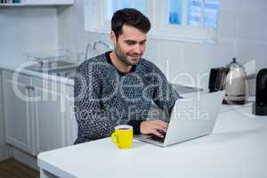 Man using laptop in the kitchen