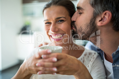 Man kissing woman on cheeks while having coffee