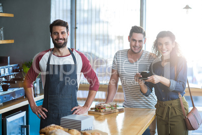 Waiter and customers standing at counter in cafÃ?Â©