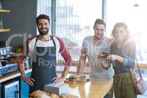 Waiter and customers standing at counter in cafÃ?Â©