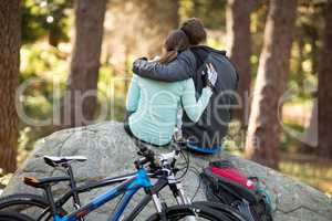 Biker couple sitting on rock in forest