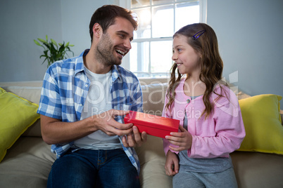 Father giving gift to daughter in the living room