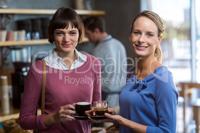 Female friends interacting while having a cup of coffee in cafÃ?Â©