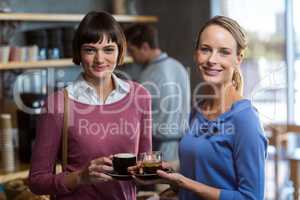 Female friends interacting while having a cup of coffee in cafÃ?Â©