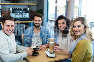 Smiling friends having a cup of coffee and cold coffee in cafÃ?Â©