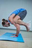Man performing crow pose on exercise mat