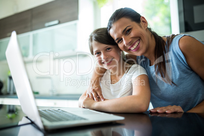 Portrait of mother and daughter using laptop and digital tablet in the living room