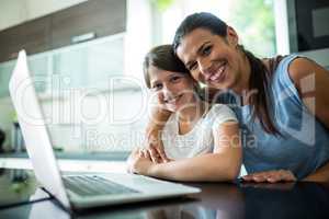 Portrait of mother and daughter using laptop and digital tablet in the living room