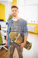 Portrait of handsome executive with skateboard at creative office