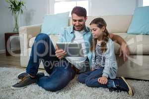 Father and daughter using digital tablet in the living room