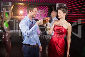 Smiling couple toasting glass of beer and cocktail