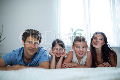 Portrait of parents and kids lying in bedroom