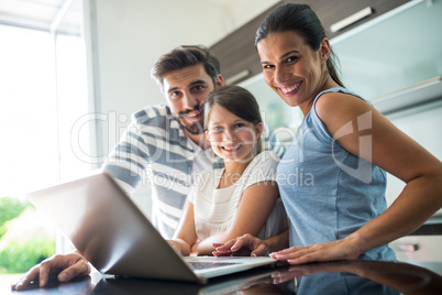 Portrait of happy family using laptop in the living room
